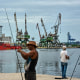 A fisherman prepares his fishing rod in front of the Colombian Navy ship ARC Carib in Havana.