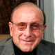 Clive Davis sits at a desk in an office by a window