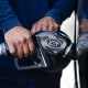 Close up of hands holding a gas pump inserted into a car