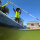 A U.S. National Park Service employee uses a vacuum pump to clean algae off the bottom of the newly repainted Lincoln Memorial Reflecting Pool