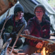 Amber Asay, left, and Jill Ashock light a fire outside while sitting underneath a tent