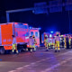 Emergency workers in fluorescent safety gear in front of ambulances at night.