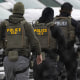 ICE agents walk in line.