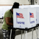 A person stands at a voting booth