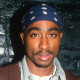 Tupac Shakur stands up again a brick wall painted black