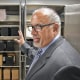 Stephen Diamantoni gestures toward an open filing cabinet filled with black boxes of cremated remains.