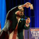 A man wipes off a glass teleprompter screen on a red, white and blue stage.
