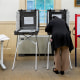 A voter casts their ballot at the Wenham Museum