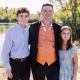 A portrait of a father and two children dressed in formal wear on the banks of a river.