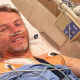 Image: Ollie Millroy lying in a hospital bed, wearing a nasal cannula.