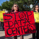 People hold anti-AI data center signs while protesting outside