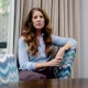 Lisa Parker looks directly toward the camera while seated at a dining table at home.