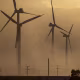 Wind turbines are partially obscured by a dust storm.