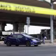 A dark blue Toyota car appears to have bullet holes while parked at an intersection behind yellow tape.