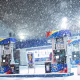 Snow falls by a gas station.