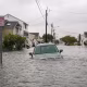 A car is seen submerged in water on a flooded road.
