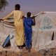 wo boys peer over a UNHCR aid tent at a camp in Chad for refugees from Darfur in Sudan