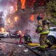 Firefighters aims hoses spraying water at a damaged building on fire