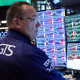 A trader looks at multiple computer screens at a desk