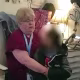 A child with their face blurred out is held by a teacher inside of a classroom