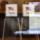 Three voting booths seen through a reflective window.
