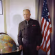 Portrait of Dwight Eisenhower standing between a large globe and an American flag