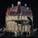 Two women put the final touches on a scale replica of a castle in a darkened room.