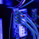 Networking cables plugged into glowing ports on the back of computing hardware.