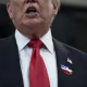 Donald Trump is seen from the nose down while wearing an I VOTED sticker on his lapel.