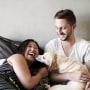 Image: Couple reclining on bed playing with dog
