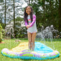 Little girl in her backyard, standing up on her blue waterslide as it squirts out water