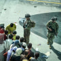 U.S. soldiers stand guard as Afghan people wait at Hamid Karzai International Airport in Kabul on Aug. 16, 2021.