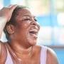 Close-up portrait of a woman at the gym laughing.