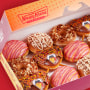 A dozen fall-themed donuts in a takeout box