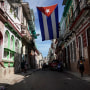 People walk under a Cuban flag hanging in downtown Havana on Oct. 8, 2021.
