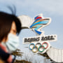 A woman walks past the Beijing 2022 Winter Olympic logo at an installation featuring National Speed Skating Oval in Beijing on Jan. 18, 2022.
