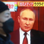 Un hombre camina en Tokio, Japón, frente a una pantalla de television que muestra al presidente ruso, Vladimir Putin. Rusia ha emprendido una campaña global de desinformación.
