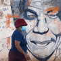 Una mujer con mascarilla pasa delante de un mural del expresidente de Sudáfrica Nelson Mandela, en Katlehong, al este de Johannesburgo, el viernes 29 de abril de 2022.