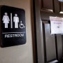 A unisex sign and the "We Are Not This" slogan are outside a bathroom at Bull McCabes Irish Pub on May 10, 2016 in Durham, N.C.