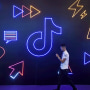 A man holding a phone walks past the TikTok, logo at the International Artificial Products Expo in Hangzhou, China on Oct. 18, 2019.