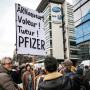 A demonstrator holds a placard reading "Scammer, thief, killer, Pfizer" during a protest against the vaccine pass and Covid-19 in front of the Pfizer headquarters, in Paris, on Jan. 29, 2022.