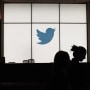 Employees walk past a Twitter logo