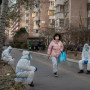 Un peatón camina junto a trabajadores de control de epidemias que trabajan en saneamiento y llevan EPI para protegerse de la propagación del COVID-19, el 6 de diciembre de 2022 en Pekín, China. 