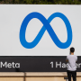 A person takes photos of the"Meta" sign in Menlo Park, Calif.