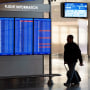 A person walks past a video board showing flight delays at Ronald Reagan Washington National Airport in Arlington, Va., on Jan. 11, 2023. 