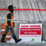 Un trabajador pasa por delante de un cartel de contratación en una obra, el miércoles 25 de enero de 2023, en Portland, Maine.
