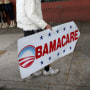 Image: Pedro Rojas holds a sign directing people to an insurance company where they can sign up for the Affordable Care Act, also known as Obamacare