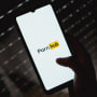 Image: The Pornhub logo on a phone screen in a dark room.
