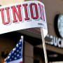 A protester waves a union sign near the Country Club Plaza Starbucks