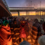 Migrants keep warm by a fire at dawn after spending a night alongside the U.S.-Mexico border fence on Dec. 22, 2022 in El Paso, Texas.